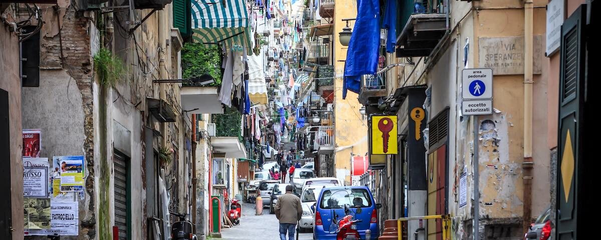 Vicolo frequentato dei Quartieri Spagnoli con turisti, botteghe e scooter